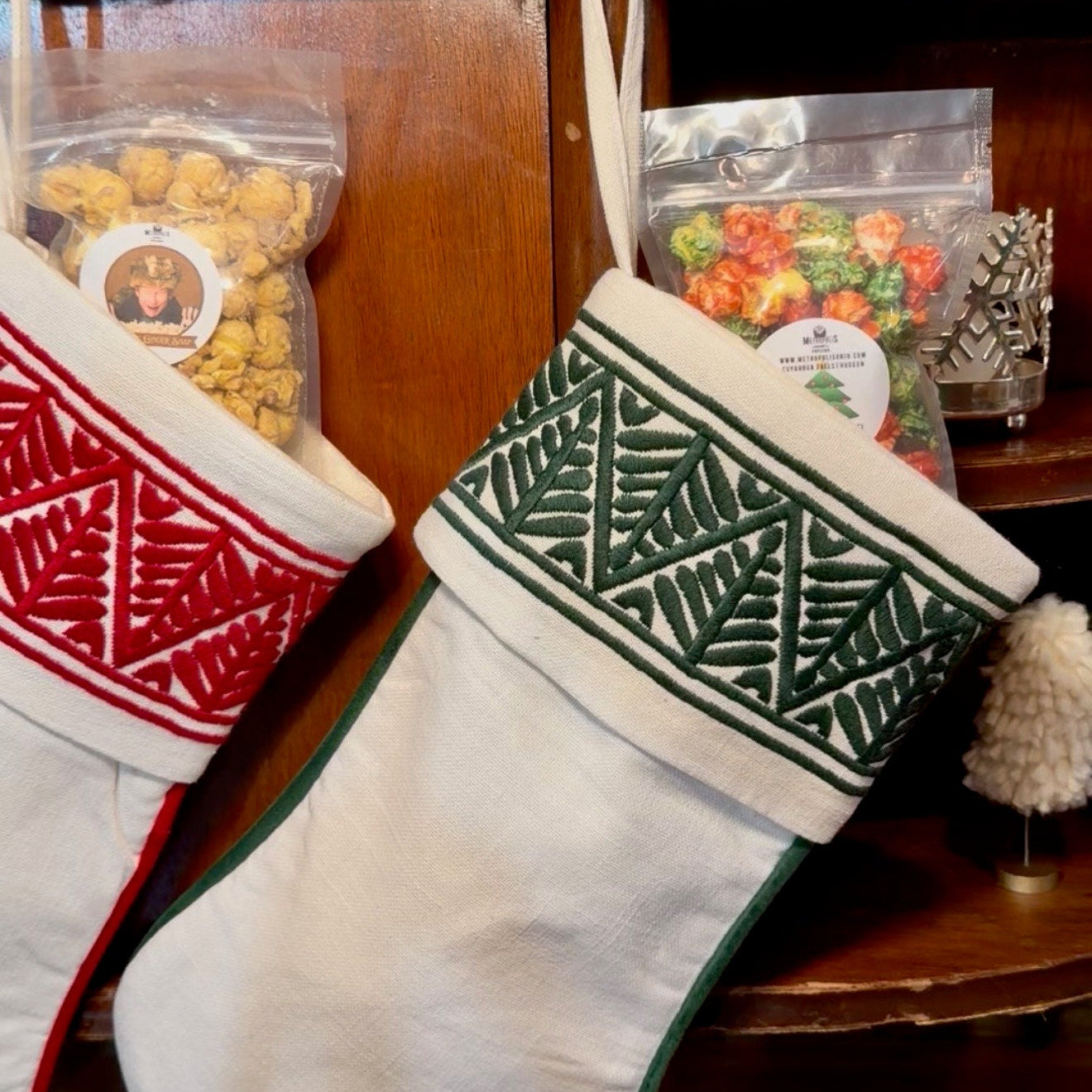 Two Christmas stockings with decorative patterns hanging on a wooden surface.